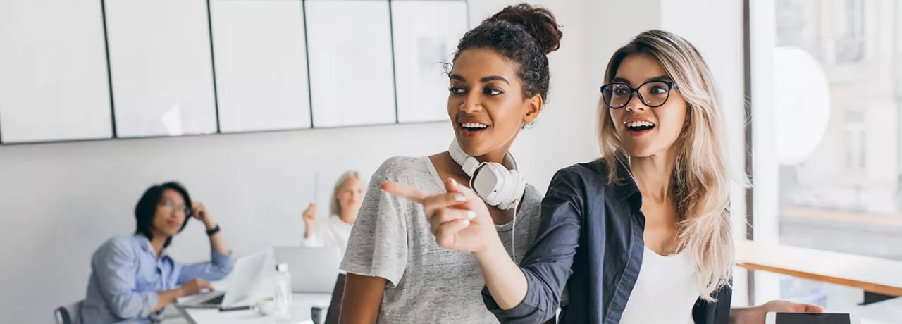 Duas colegas de trabalho conversam no escritório