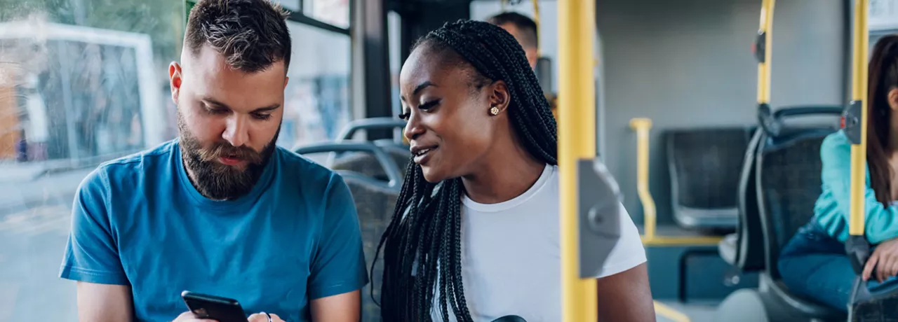 Dupla de amigos confere as notícias enquanto vão para o trabalho de ônibus