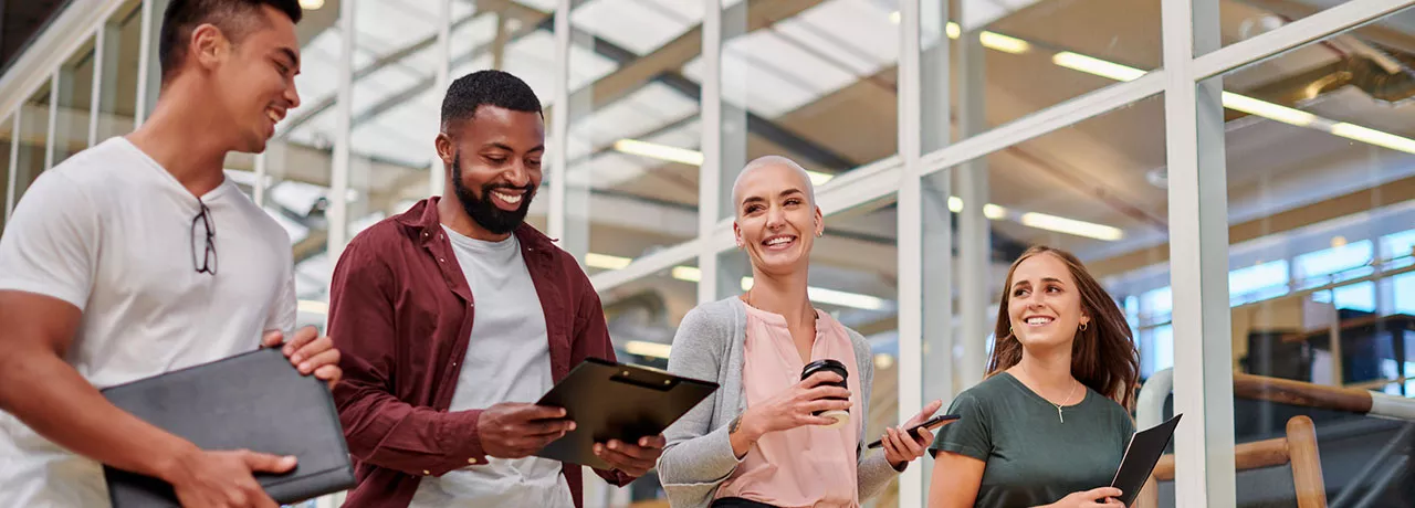 Na foto, quatro jovens profissionais conversam animados depois de uma reunião importante