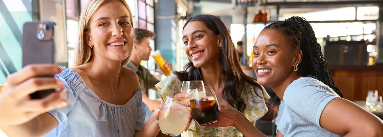 Foto mostra 3 amigas tirando uma foto juntas no restaurante