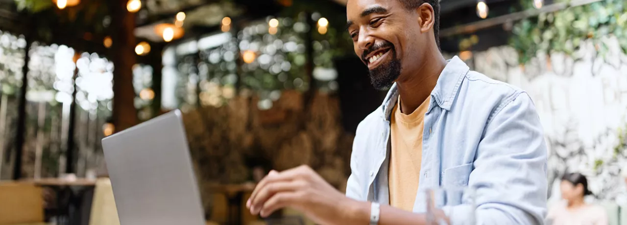 Homem trabalha no seu computador e sorri