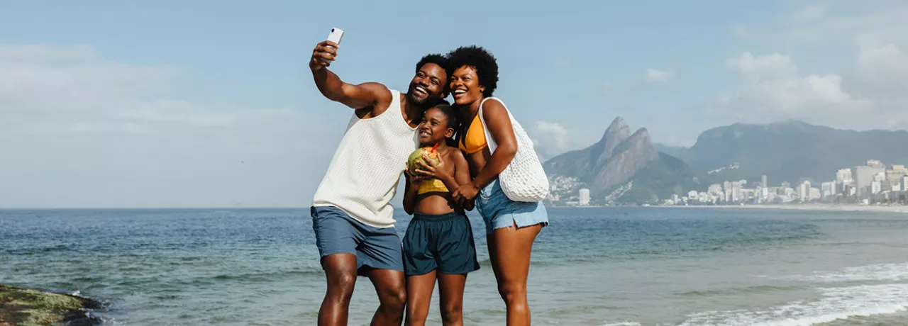 Foto mostra família (pai, mãe e filha) tirando uma selfie no Rio de Janeiro