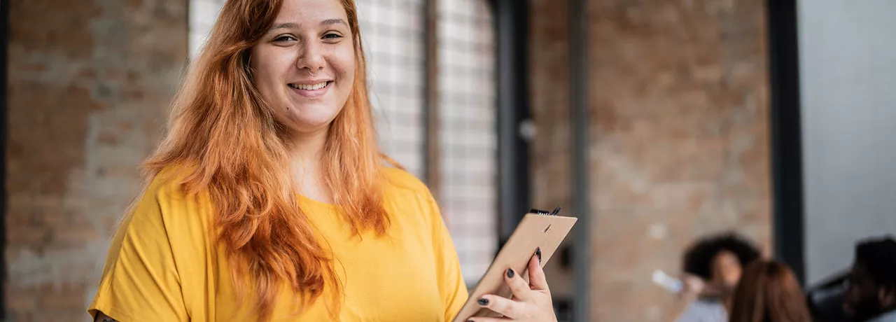 Jovem empresária sorri para a câmera segurando um tablet