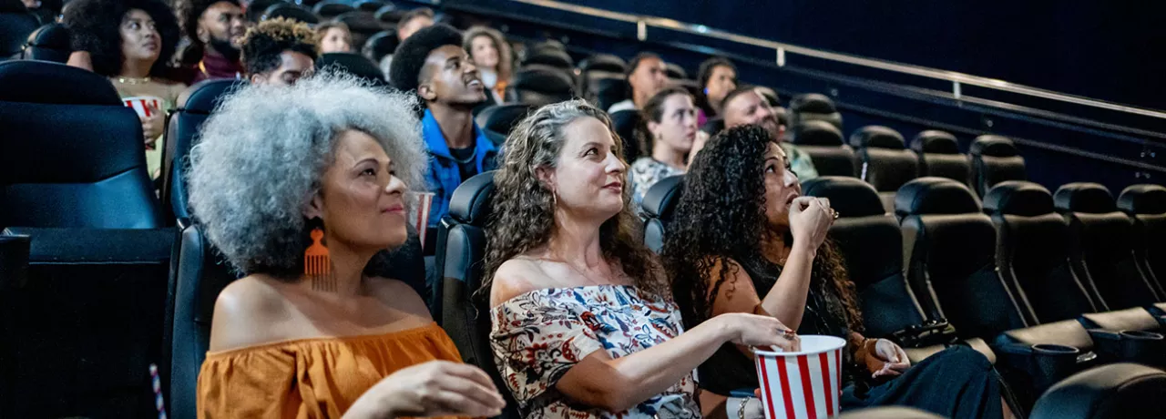 Três amigas assistem um filme brasileiro no cinema