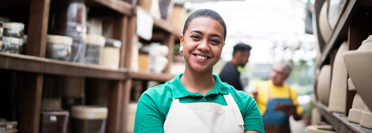 Foto mostra funcionária de uma loja de cerâmicas sorrindo para a câmera