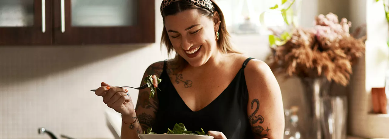 Mulher come uma salada na copa da empresa
