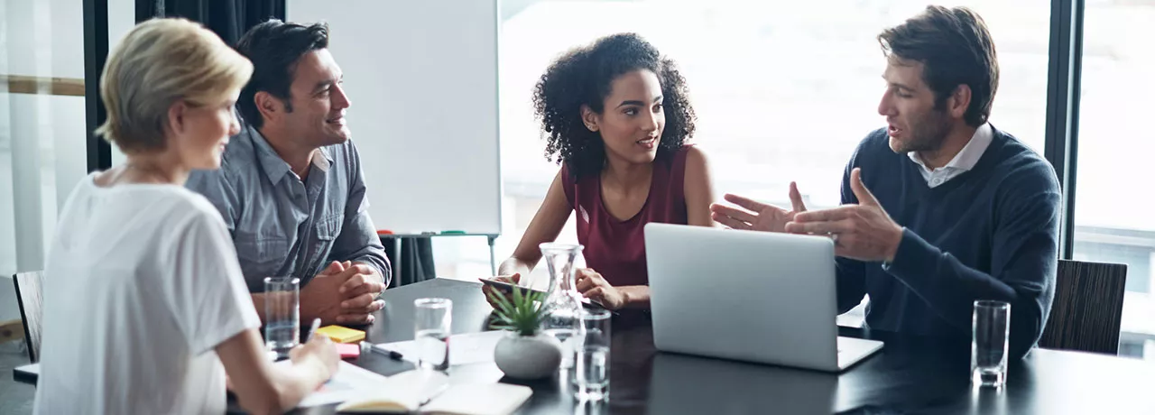 4 pessoas discutindo algo em mesa de reunião.
