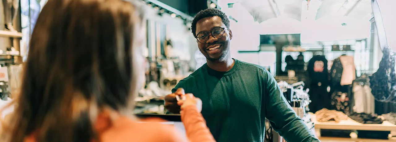 homem pagando compras enquanto sorri.
