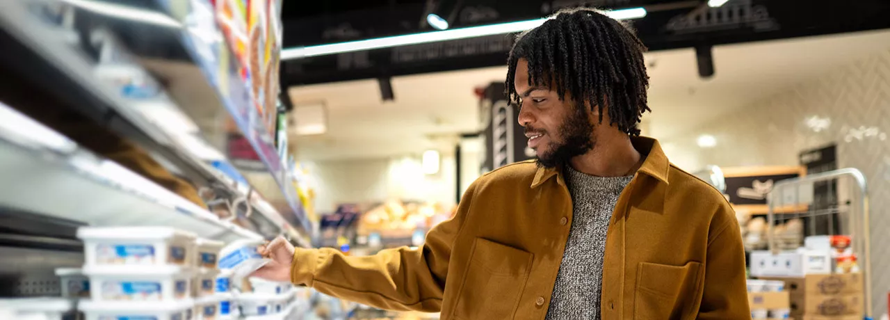 homem escolhendo itens de uma prateleira do supermercado.
