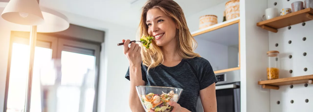 Imagem mostra uma mulher loira comendo salada