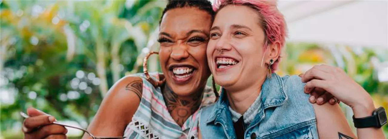 Imagem mostra duas mulheres abraçadas sorrindo e comendo felizes