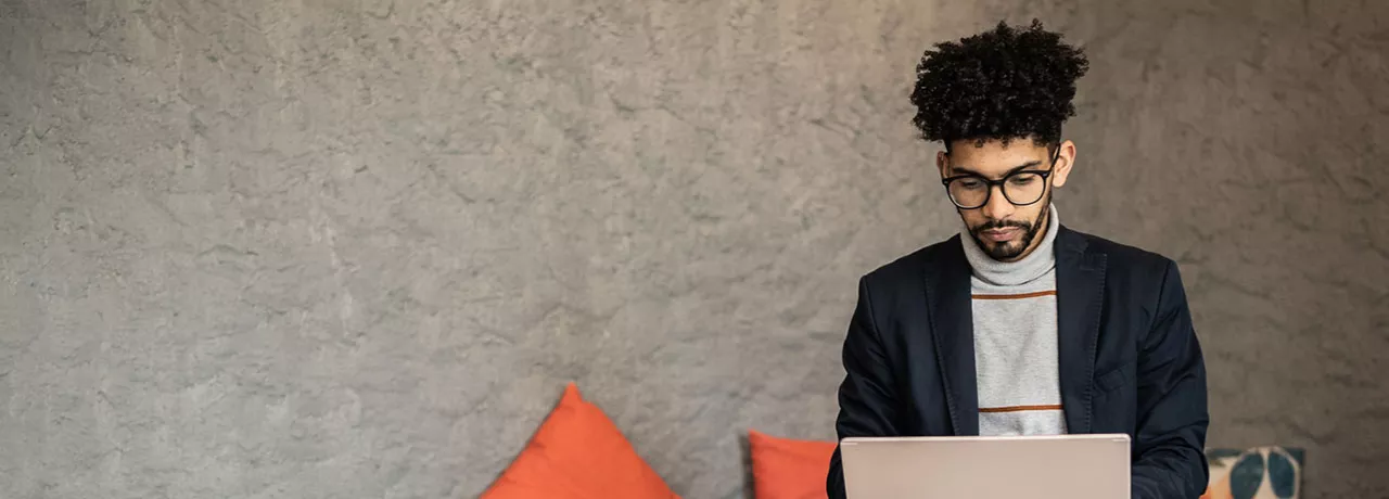 homem trabalhando com laptop no colo e semblante sério.