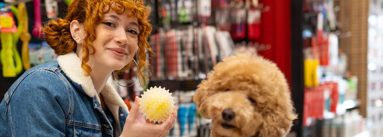 Jovem profissional compra brinquedo para seu cachorro com seu benefício flexível da empresa.