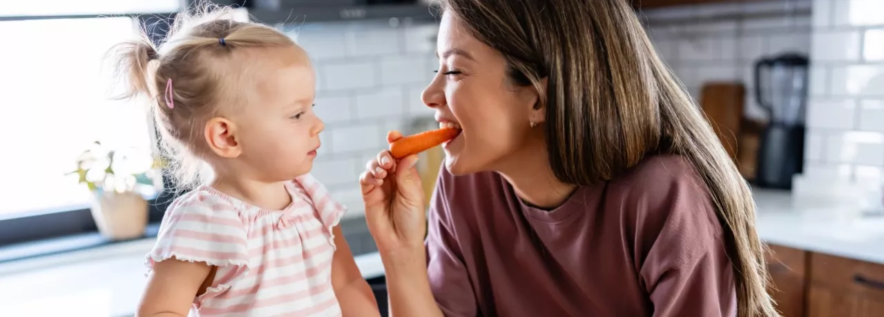 A imagem mostra uma mulher e uma criança comendo frutas