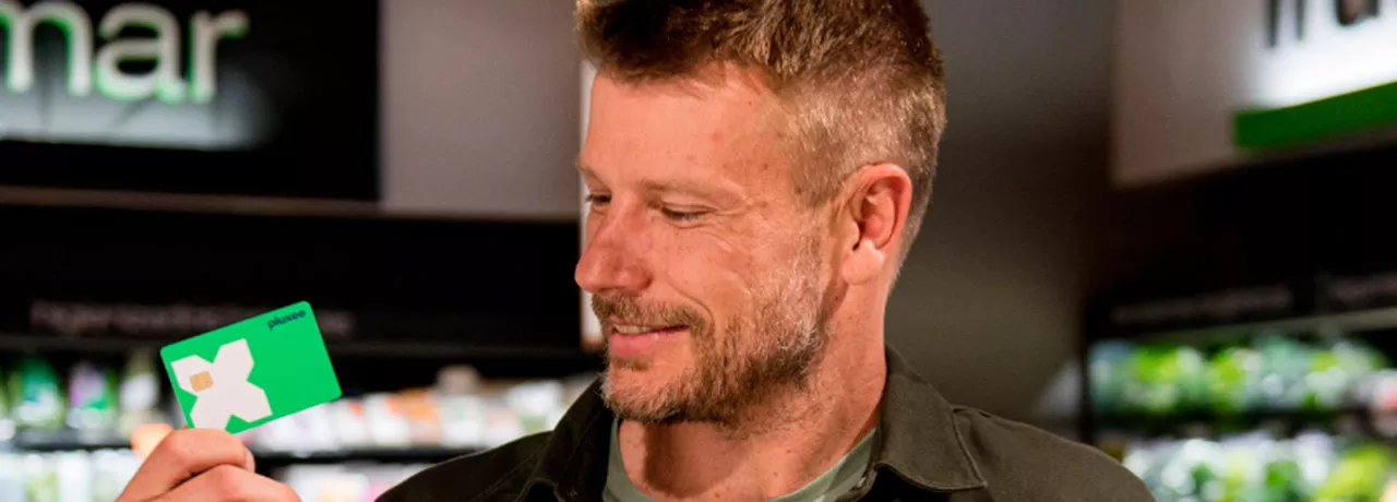 Rodrigo Hilbert segura um cartão Pluxee Multibenefícios no supermercado