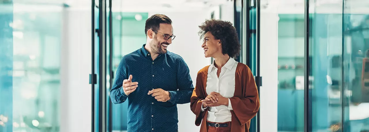 duas pessoas conversando em corredor de escritório.