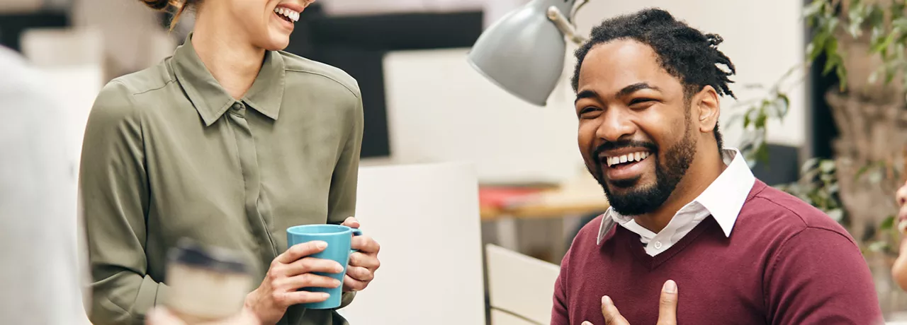 pessoas sorrindo e conversando em ambiente corporativo.