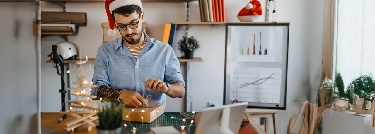 Funcionário em home office desembala um presente de Natal da empresa