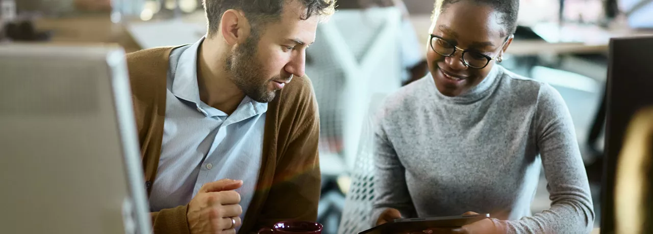 duas pessoas conversando enquanto olham algo em tablet.