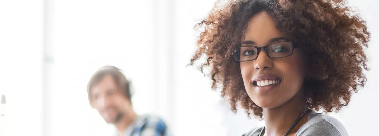 mulher sorrindo para a câmera em ambiente de trabalho.