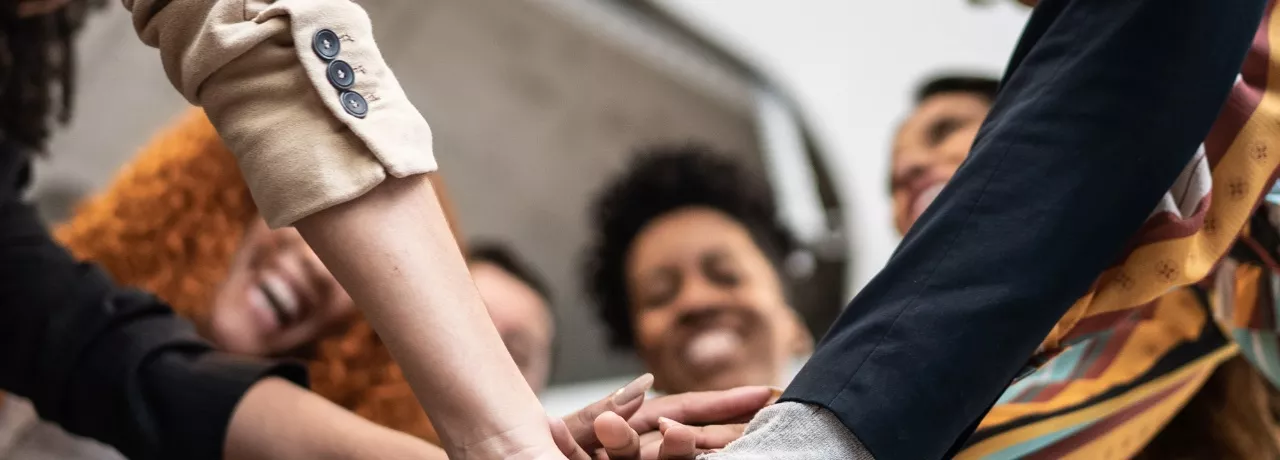 A imagem mostra um grupo de trabalhadores juntando as mãos e celebrando