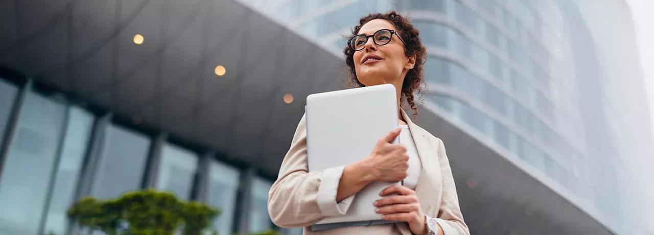 Foto mostra uma executiva em frente ao prédio em que trabalha
