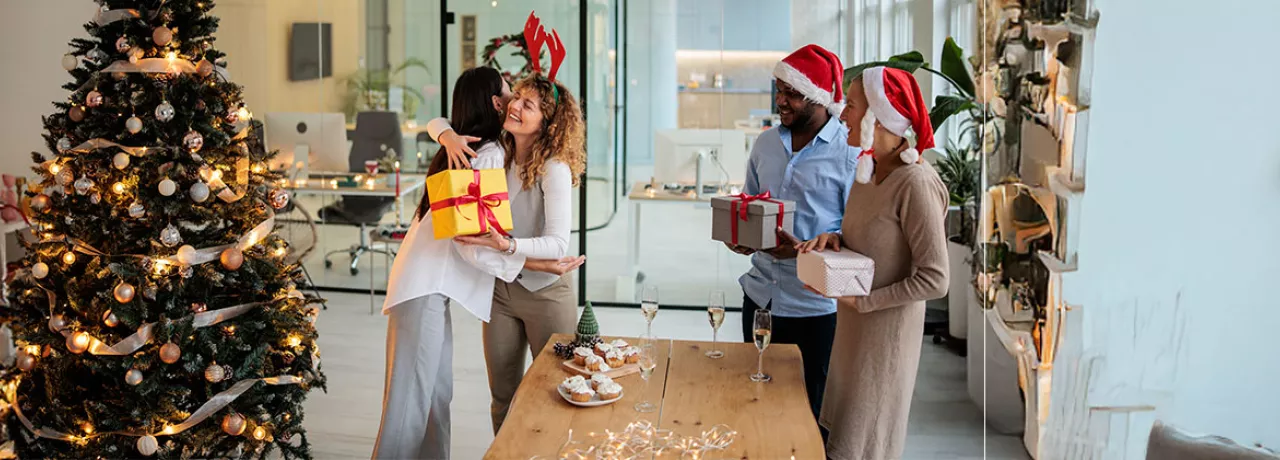pessoas trocando presentes de natal em escritório.