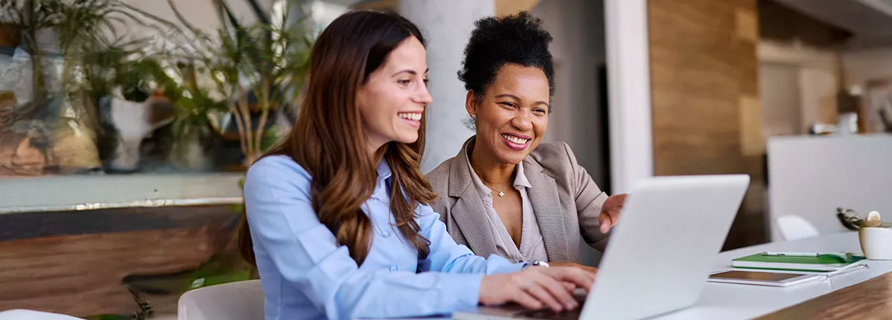 duas mulheres sorrindo para notebook.