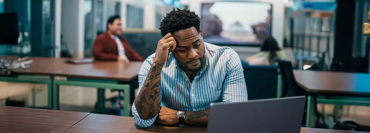 Foto mostra uma pessoa estressada no escritório