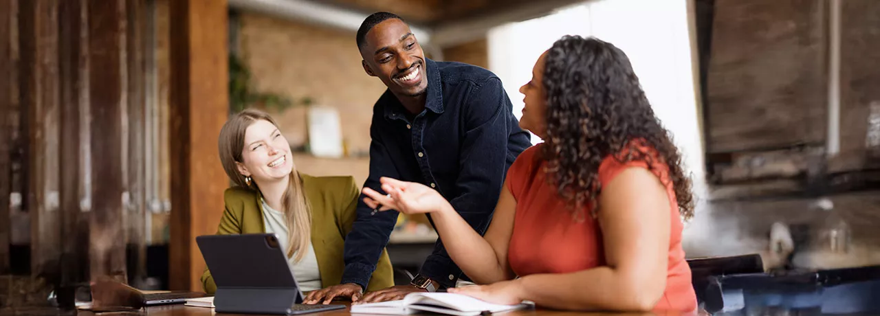 Três colegas de trabalho conversam animadamente durante uma reunião