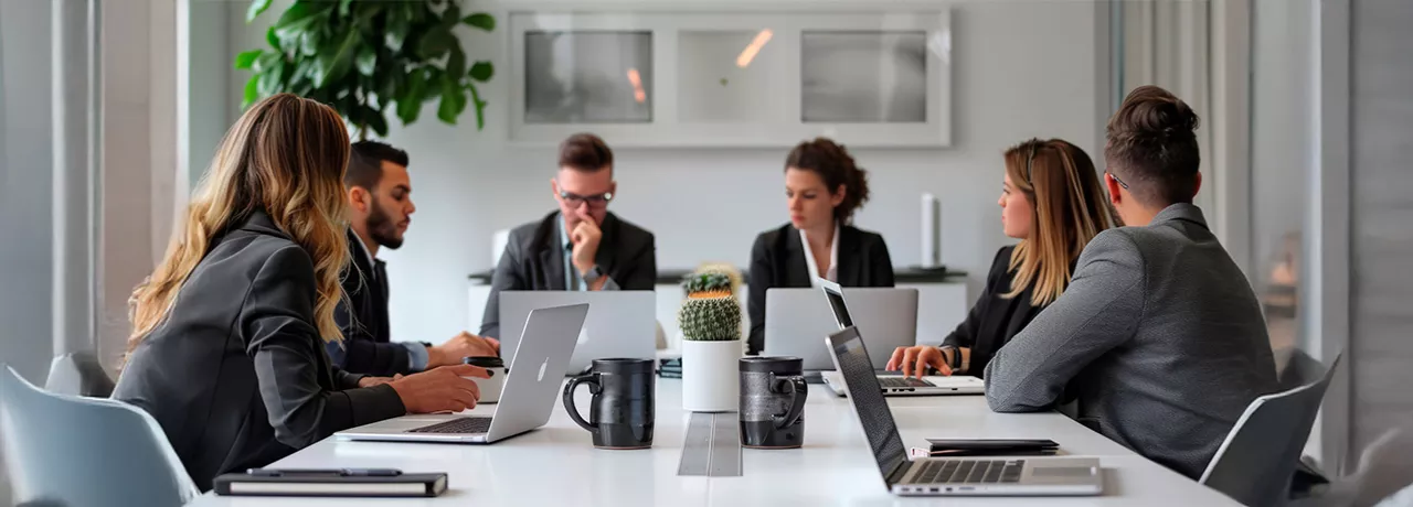 Foto mostra um grupo de pessoas trabalhando juntas para alinhar os objetivos da empresa