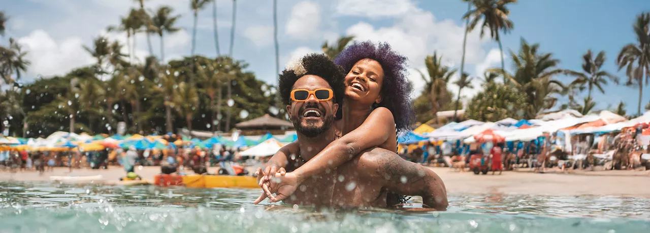 Foto mostra um casal curtindo férias na praia