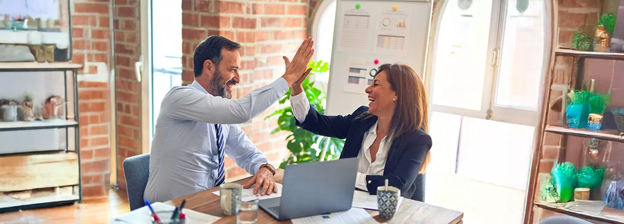 duas pessoas fazendo "toca aqui" no trabalho.