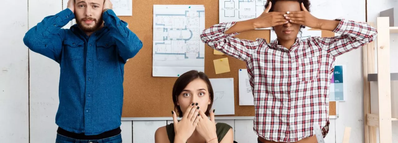 três pessoas imitando os “três macacos sábios”, da cultura japonesa.