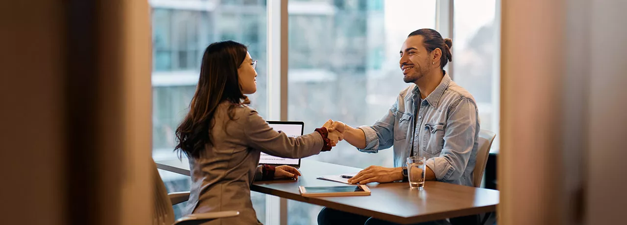 duas pessoas dando um aperto de mãos em escritório.