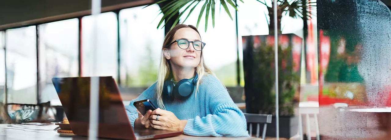 Foto mostra uma pessoa trabalhando em um notebook em uma sala ampla