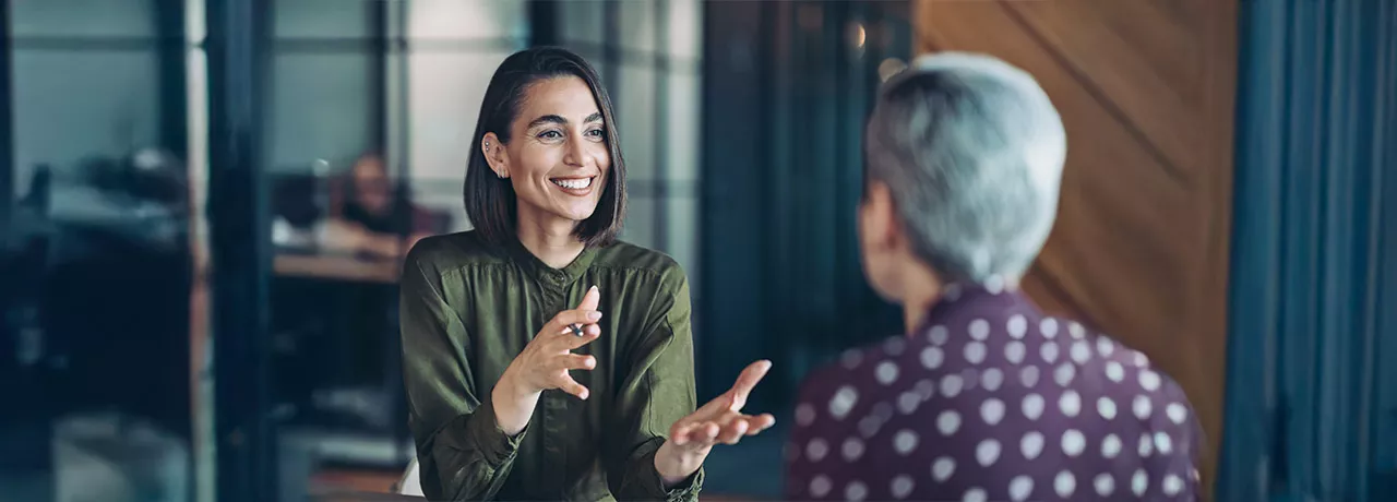 duas mulheres conversando em um ambiente corporativo 