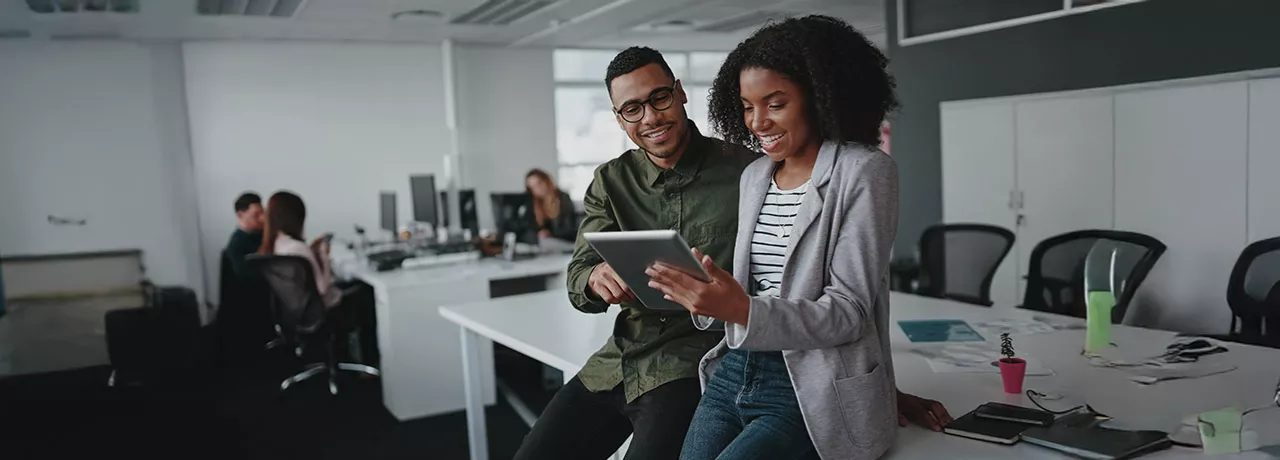 duas pessoas olhando informação em tablet no escritório.