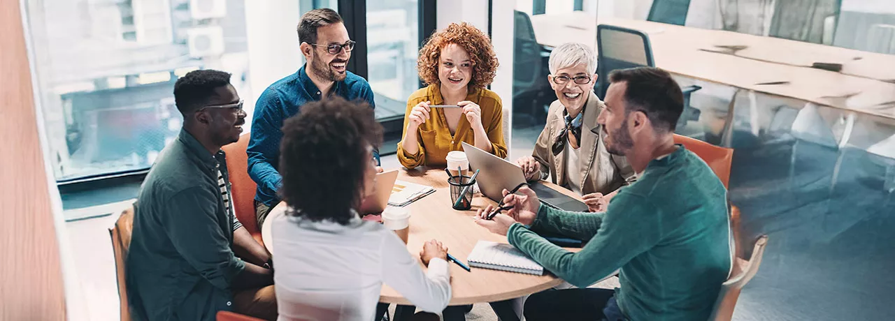 time conversando em torno de uma mesa dentro de escritorio.