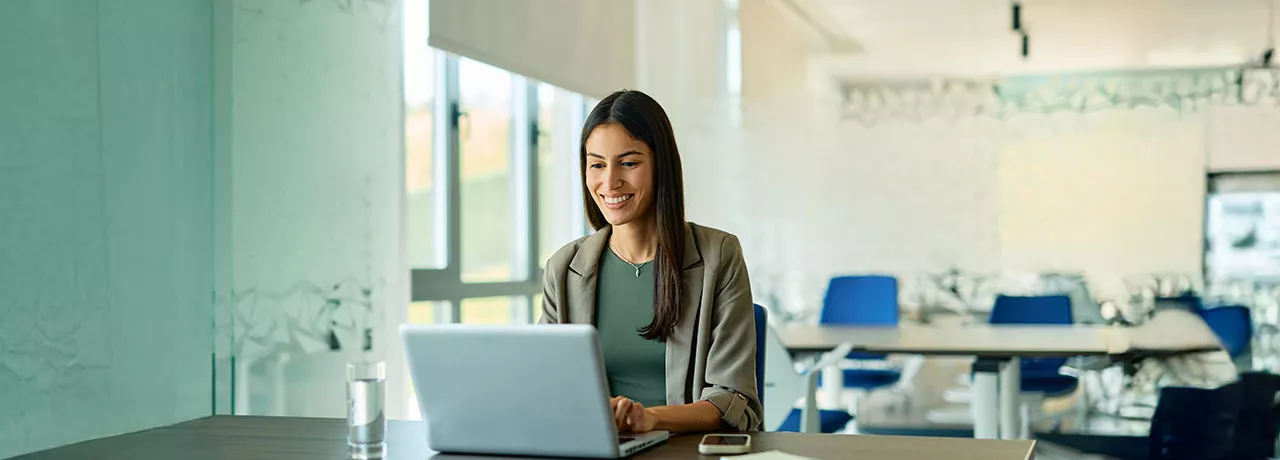 mulher sorrindo enquanto usa o computador no trabalho.