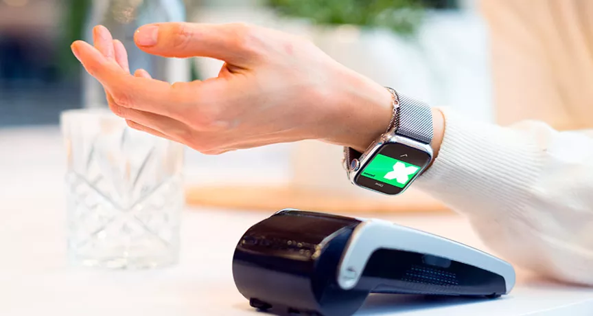 Tecnologias do futuro do varejo sendo ilustradas por uma mulher pagando sua conta usando seu smartwatch