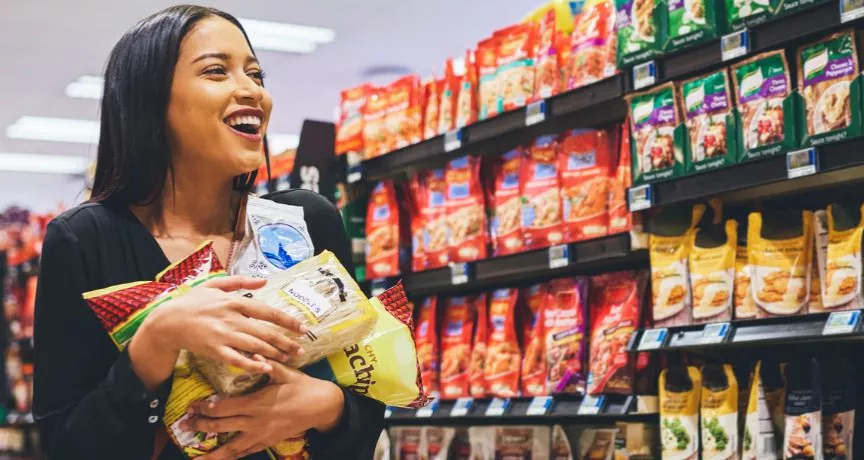 Mulher se diverte fazendo compras no supermercado com seu vale-alimentação