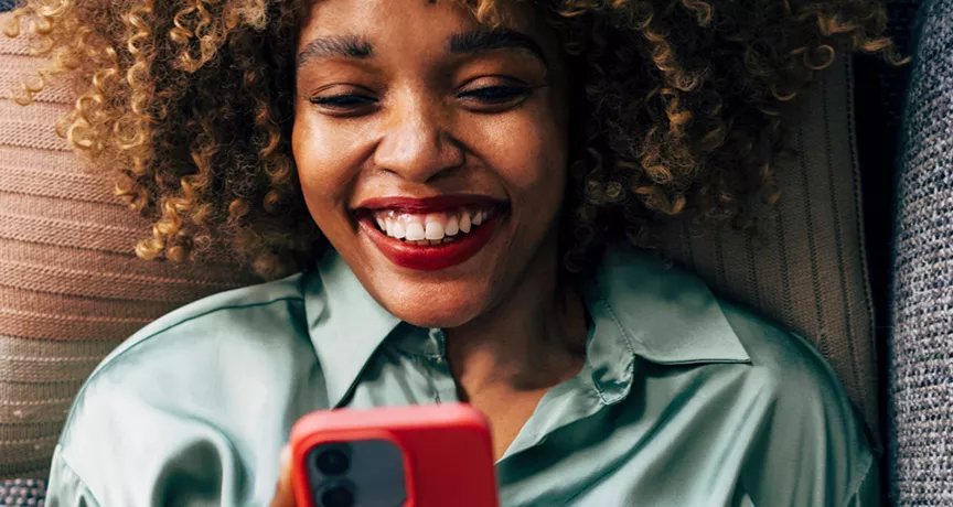 Mulher deitada no sofá confere as ofertas do app Pluxee Brasil