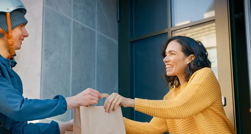 Mulher recebe delivery no local de trabalho. Ela pediu no Rappi usando o cartão Pluxee Refeição