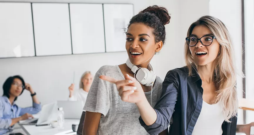 Duas colegas de trabalho conversam no escritório