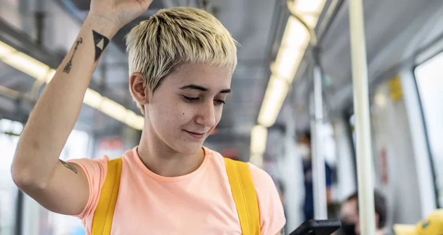Jovem profissional vê o celular enquanto faz o caminho até o trabalho