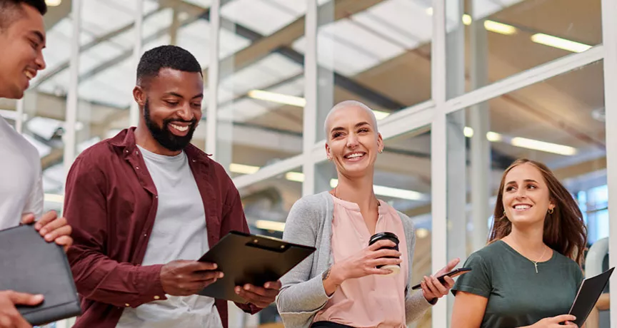Na foto, quatro jovens profissionais conversam animados depois de uma reunião importante