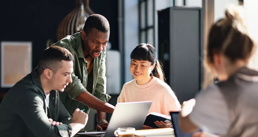 Foto mostra uma equipe com pessoas de diversas origens trabalhando juntas