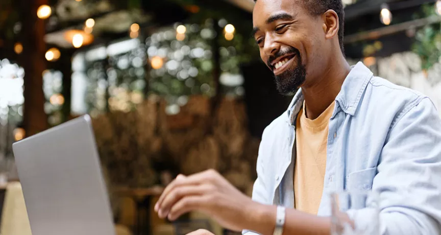 Homem trabalha no seu computador e sorri