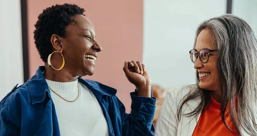 Duas colegas de trabalho conversam animadas durante o expediente